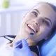 mujer sonriendo y mano de dentista